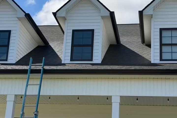 Clean white gutter and fascia against a washed home with dark windows